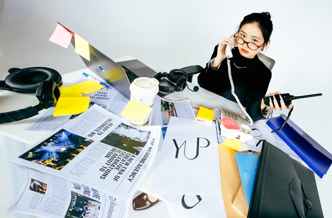 Photo by Chu CHU Woman on phone at messy desk with papers and laptop